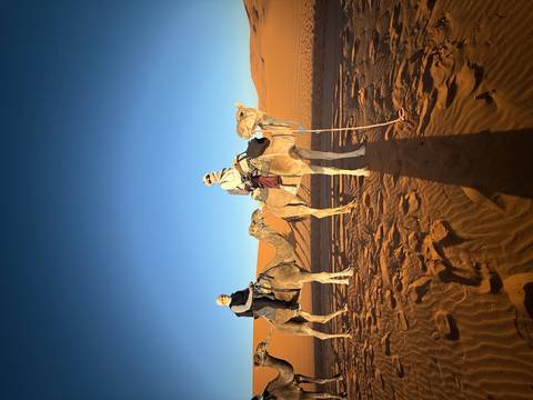       Two people riding camels in the desert during daylight.
  
