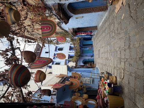       A picturesque street with colorful baskets hanging above.
  