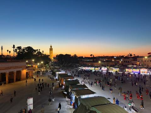       A bustling market square during sunset, with a tower in the background.
  