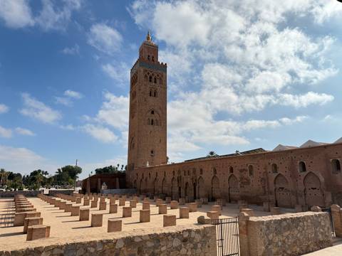       A tall historic tower and an open courtyard under a blue sky.
  