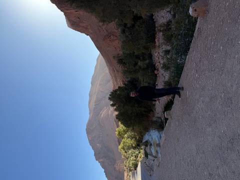       A man posing in front of a mountainous landscape with a river.
  