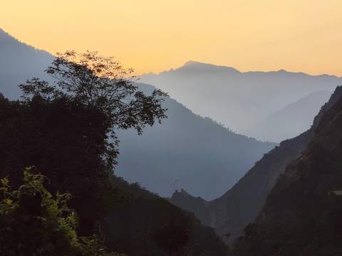 A serene view of mountains with mist and a golden sunrise.