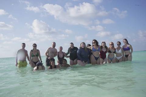       Group photo of people standing in the ocean.
  
