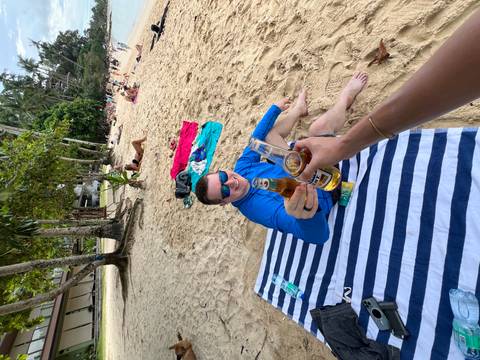 People toasting with beers on a sandy beach.