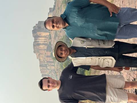 Three people posing with a fort in the background.