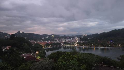       Scenic view of a city with a lake and hills during dusk.
  