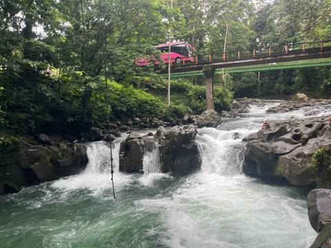 A river with a bridge overhead and waterfalls.