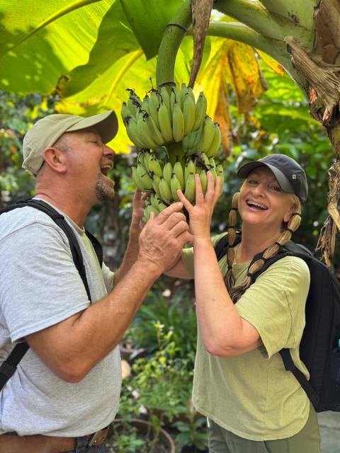 Couple interacting with a bunch of bananas in a garden.