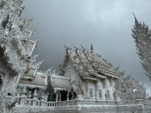       Intricately designed white temple with cloudy sky.
  
