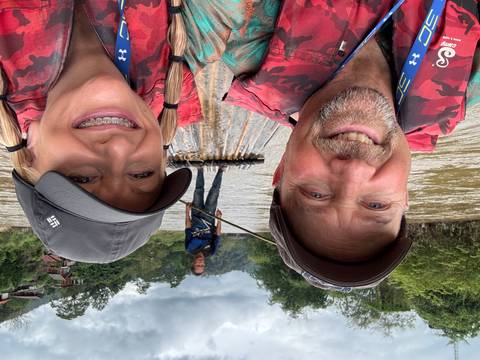 Couple on a river raft with a guide paddling.
