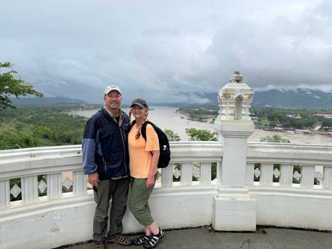       Couple posing at a viewpoint with river and landscape.
  