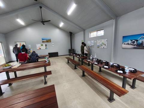       Inside a community hall with benches and people.
  