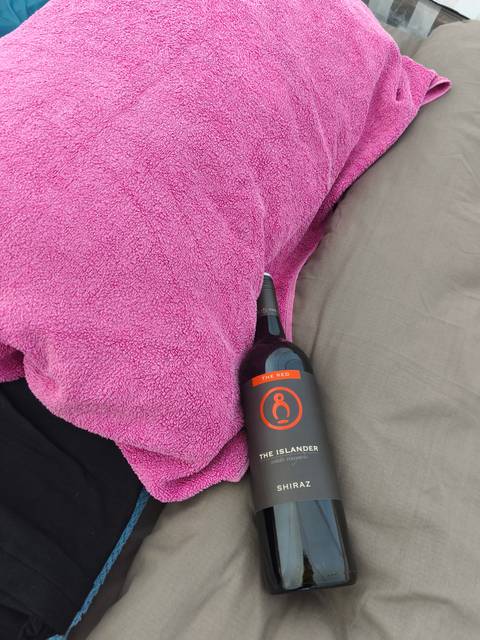       Bottle of wine partially covered by a pink blanket.
  