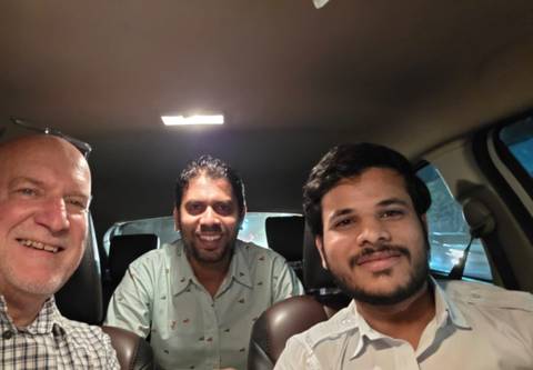       Three people sitting in a car smiling at the camera.
  