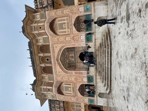       Facade of a richly decorated historical building with visitors.
  
