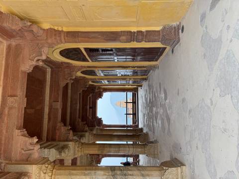       Historic corridor with ornate columns and a distant view.
  