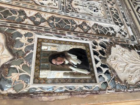 A person reflected in an ornate mirror.