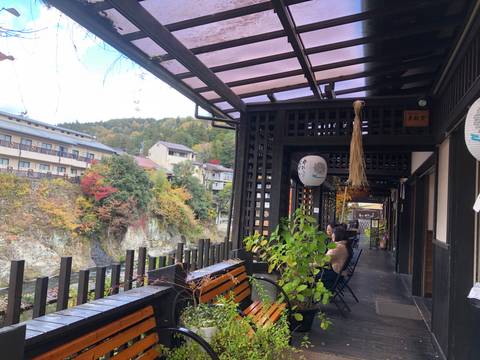 Wooden deck overlooking a scenic river and autumn foliage.