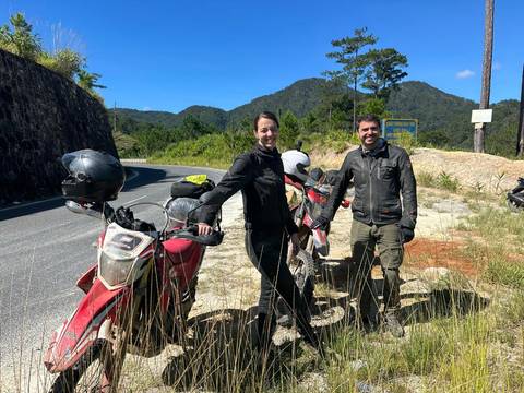 Motorcyclists posing beside their bikes on a scenic road.