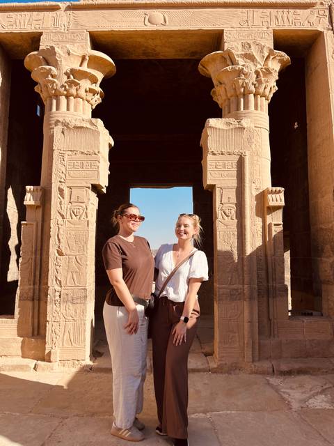 Two women smiling in front of an ancient Egyptian stone structure.