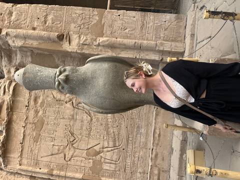Woman posing with ancient Egyptian falcon sculpture.