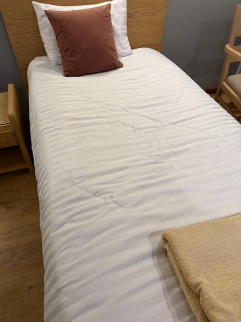       Close-up of a white rumpled bed cover in a hotel room.
  