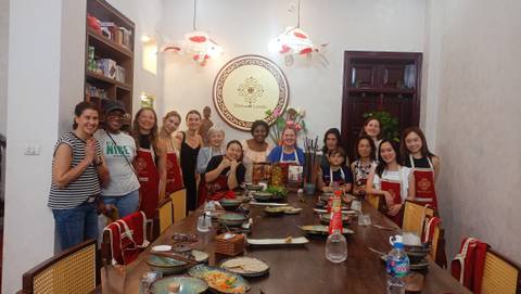 Large group of people gathered around a table at a cooking class.