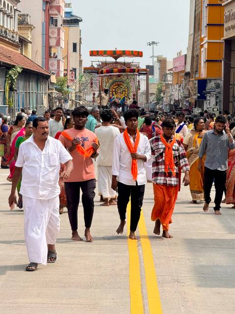 Group of people walking on a busy street during a cultural event.