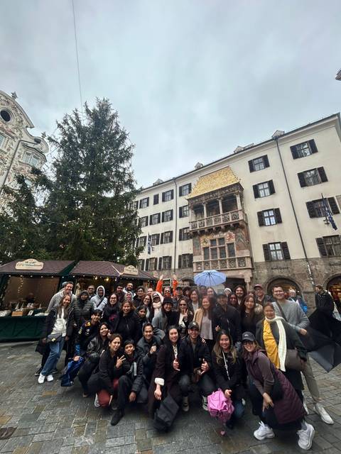 Group of tourists in front of a historical building at a Christmas market.