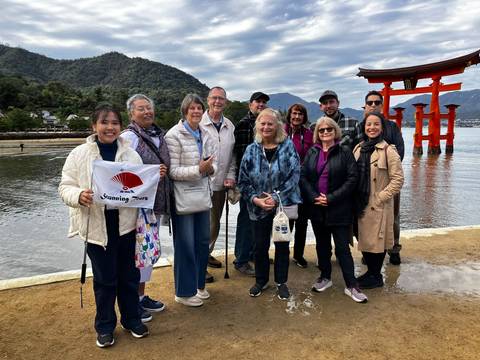 Group of tourists posing with the famous torii gate in the background.