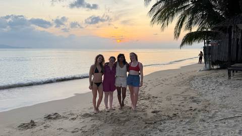 Four people on a beach during sunset.
