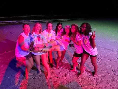 Group of women celebrating on a beach at night.