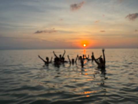       Blurred image of people in water during sunset.
  