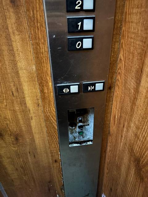 Close-up of elevator buttons and wood panel.
