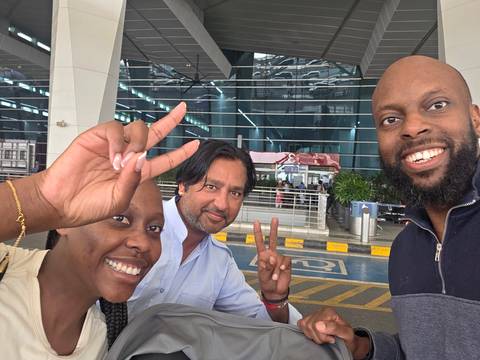       Group of travelers posing at an airport entrance
  