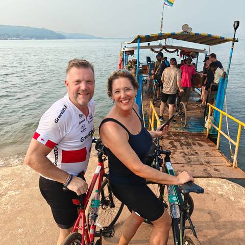 Two cyclists on a dock with others boarding a ferry.