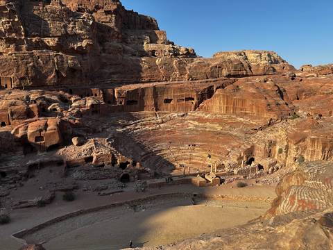 Amphitheater carved into red rock cliffs with sunlit surroundings.