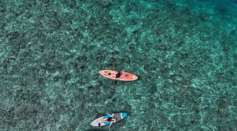       Kayakers on clear turquoise water, seen from above.
  