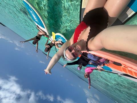       A group of friends posing on paddleboards in clear water.
  