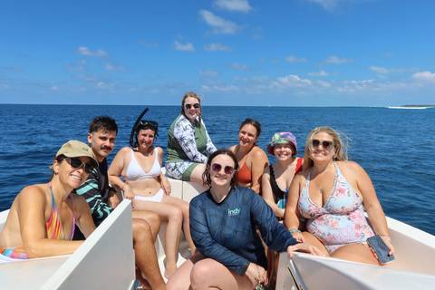       A group of people enjoying a boat ride on clear blue waters.
  