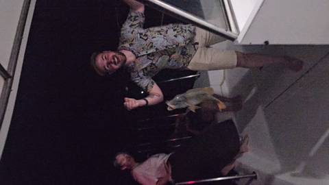       A nighttime fishing scene on a boat with people displaying their catch.
  