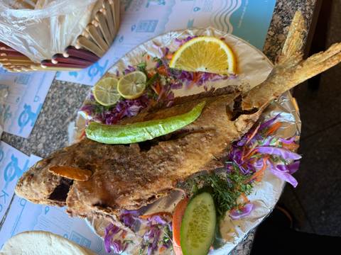 Fried fish served on a platter with salad and lemon slices.