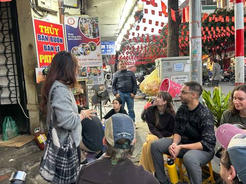 Group of people sitting and talking on a busy street with signs.