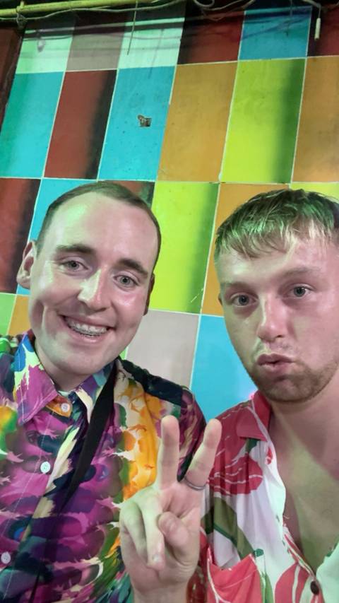 Two smiling people in colorful shirts with a colorful background.