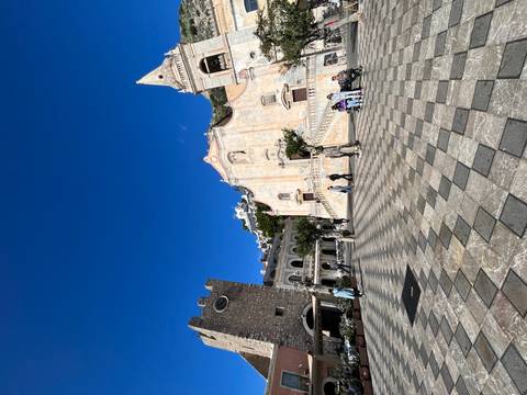 Historic square with buildings and people sitting around.