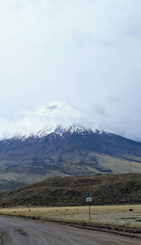       Snow-capped Cotopaxi volcano partially covered by clouds.
  