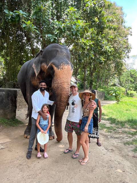 Family posing with an elephant in a natural setting.