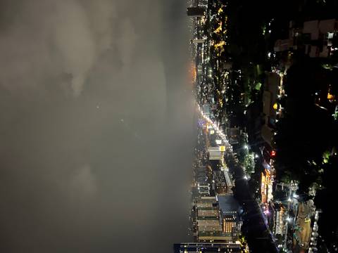       Cityscape view, with illuminated buildings under a cloudy sky.
  