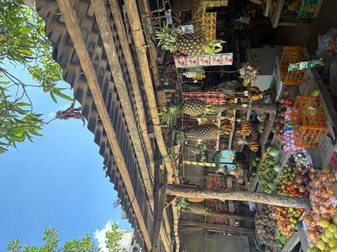       Fruit stall at an outdoor market with pineapples and bananas.
  