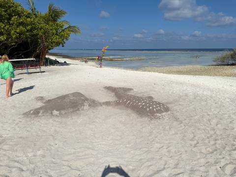       People exploring a beach with sand sculptures.
  